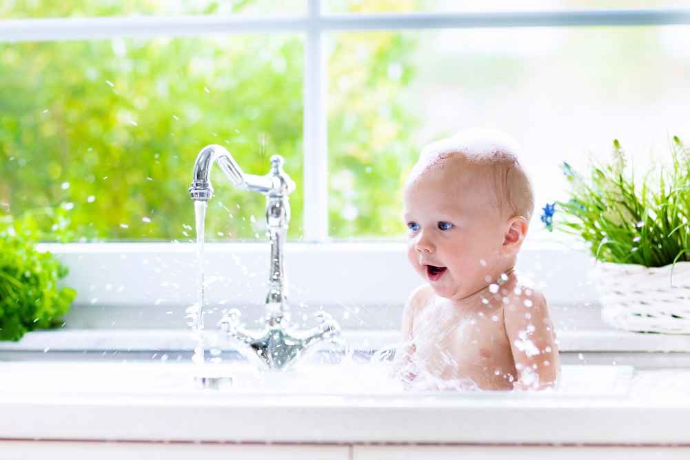 Baby taking a bath in the kitchen sink